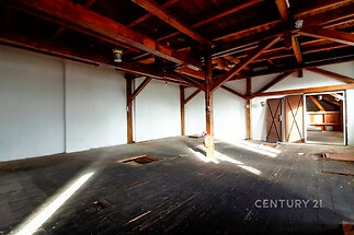 Podkrovní prostor s dřevěnými trámy, starší parketová podlaha, přirozené světlo skrze střešní okna, vhodný pro renovaci, loftový styl.