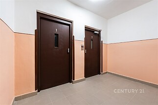 Vstupní hala bytového domu s dlažbou, moderní výtahy a světlé stěny v kombinaci oranžové a bílé barvy.