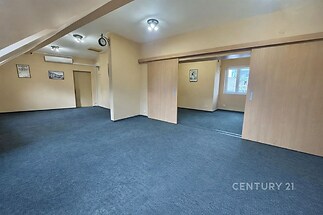 Prostorný obývací pokoj s modrým kobercem, posuvnými dřevěnými dveřmi a světlým stropem, nabízí moderní flexibilní prostor.