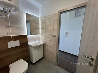 Malá koupelna s moderní dlažbou, světlý obklad, sanitární zařízení včetně umyvadla a toalety, čistý a udržovaný prostor.