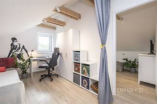 Světlá podkrovní pracovna s parketovou podlahou, velkými okny a moderním nábytkem, ideální pro kreativní práci nebo studium.