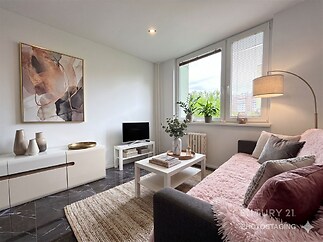 Světlý obývací pokoj s moderní dlažbou, velkými okny a elegantním nábytkem.