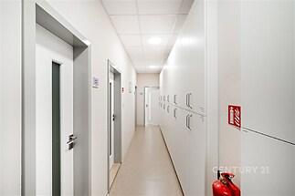 Průchozí chodba s dlažbou, vestavěnými skříněmi a moderními dveřmi, vhodná pro kancelářské prostory.