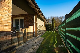 Zahradní terasa s dlažbou, cihlový obklad na fasádě, moderní styl, oplocení zajišťuje soukromí, zelený trávník vedle terasy.