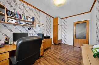 Pracovna s parketovou podlahou, vestavěné skříně a dřevěným nábytkem, poskytující útulné pracovní prostředí.