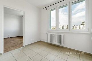Světlý pokoj s dlažbou, velká okna a moderní topení, přístup do další místnosti s parketovou podlahou, světlý a prostorný interiér