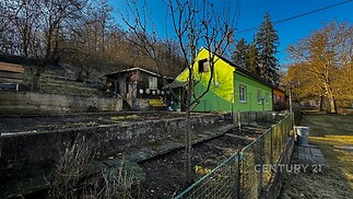 Zahrada s rodinným domem, zelená fasáda, přírodní okolí, klidná lokalita, terasovitý terén, slunný pozemek, rekreační styl.