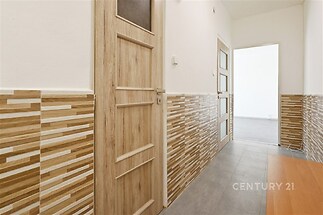 Úzká chodba s dlažbou a dřevěnými dveřmi, zdobena keramickým obkladem, působí moderně rekonstruovaným dojmem.