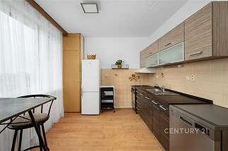 Moderní kuchyň s parketovou podlahou, vestavěnými skříněmi a velkými okny. Světlý a prostorný interiér vhodný pro rodinné vaření.