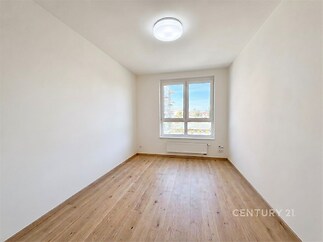 Světlá ložnice s parketovou podlahou, velkými okny a moderním osvětlením, ideální pro rekonstrukci nebo nový design.
