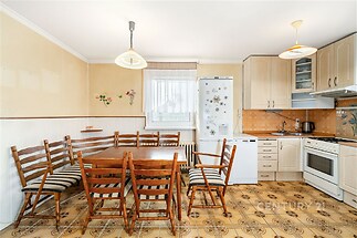 Kuchyň s retro dlažbou, dřevěným nábytkem a světlým interiérem disponuje velkým jídelním stolem a moderními spotřebiči