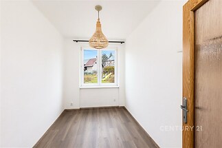 Světlá ložnice s laminátovou podlahou, velkým oknem a neutrálními bílými stěnami, ideální pro moderní interiér.