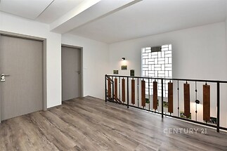 Chodba s moderním laminátovou podlahou a stylovým zábradlím, dveře v neutrálním odstínu, prostorný a světlý interiér.