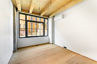 Pokoj s parketovou podlahou, dřevěný strop a velká okna. Moderní vzhled s klimatizací zajišťuje pohodlí a eleganci prostoru.