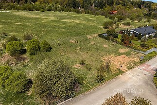 Pozemek s travnatým porostem, lemovaný vzrostlými keři, vhodný pro výstavbu; klidná lokalita poblíž lesa, dobrá dostupnost, ideální investice