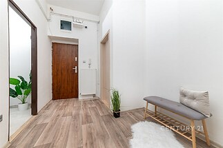 Vstupní hala s moderní vinylovou podlahou, bílými stěnami a dekorativními prvky. Světlý a prostorný interiér s kvalitními materiály.