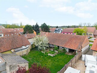 Uzavřený dvůr s trávníkem obklopený staršími domy s červenou střechou, nacházející se v klidné rezidenční oblasti