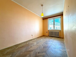 Prázdná místnost s parketovou podlahou, velké okno, světlé stěny, moderní styl, připravená k rekonstrukci či novému designu.