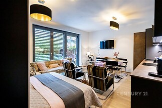 Moderní obývací pokoj s parketovou podlahou, velkými okny a elegantním nábytkem spojuje pohodlí a styl v rekonstruovaném interiéru.