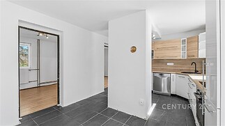 Moderní kuchyň s parketovou podlahou a vestavěnými spotřebiči, světlá, s dřevěnými prvky a dlažbou.