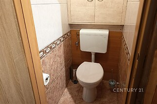 Útulná koupelna s keramickými obklady, dřevěnými detaily a praktickými úložnými prostory, vhodná pro moderní bydlení