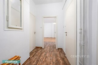 Předsíň s dřevěnou podlahou, bílými stěnami a moderními dveřmi, ideální pro vytvoření útulného vstupu do bytu.