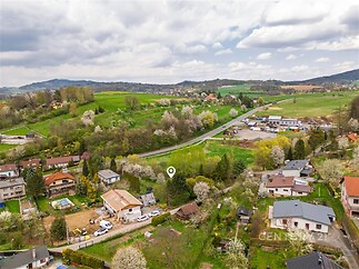Letecký pohled na venkovskou lokalitu s rodinnými domy, zahradami a zelenou krajinou, ideální pro milovníky přírody a klidné prostředí