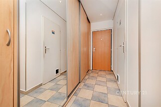 Chodba s dlažbou, vestavěnými skříněmi a moderními dveřmi, světlý interiér, čisté linie a funkční design