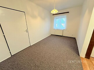 Světlá ložnice s kobercovou podlahou, velkými okny a moderním světlým interiérem, ideální k rekonstrukci či okamžitému nastěhování.