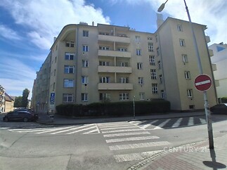 Průčelí bytového domu s renovovanou fasádou, velká okna, klidná lokalita městské části, ideální pro rodinné bydlení.