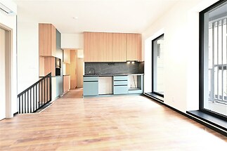 Světlý obývací pokoj s moderní kuchyní, parketová podlaha, velká okna, vestavěné kuchyňské skříně, světlý interiér, moderní styl.