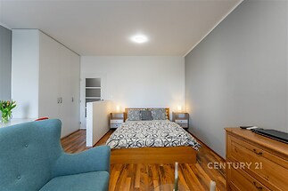 Prostorná ložnice s parketovou podlahou, vestavěnými skříněmi a moderním osvětlením, nabízí komfortní a stylový interiér.