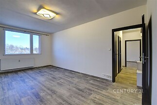 Světlý obývací pokoj s moderní parketovou podlahou a velkými okny, zrekonstruovaný interiér nabízí prostorné uspořádání.