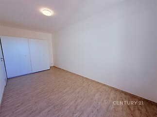 Světlá prázdná ložnice s parketovou podlahou a vestavěnými skříněmi, moderní minimalistický design, neutrální barvy pro všestrannost interiéru.