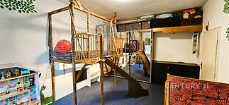 Dětský pokoj s herní konstrukcí, koberce, vestavěné skříně, moderní design, světlý prostor vhodný pro rodiny s dětmi.