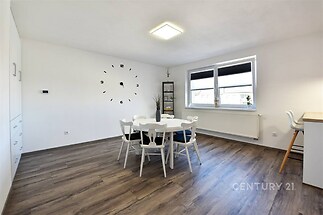 Jídelna s parketovou podlahou, moderní osvětlení, velká okna, minimalistický stylový interiér.