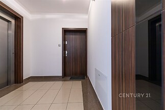Vstupní hala s moderními dlažbami, dřevěnými obklady a bezpečnostními dveřmi dodává prostor elegantnímu stylu.