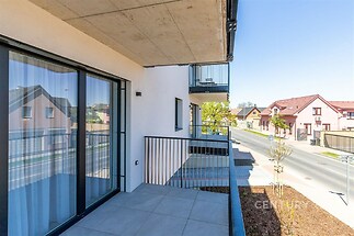 Balkon s dlažbou, výhledem na klidnou ulici a moderní architekturou, je ideální pro relaxaci a doplňuje stylové bydlení v nové zástavbě.