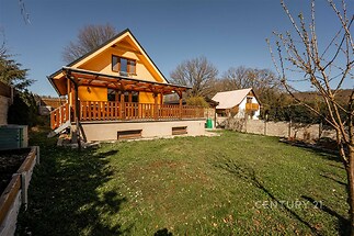 Světlá venkovská chata s dřevěnou terasou, prostornou zahradou a novou fasádou. Chata se nachází v klidné oblasti obklopené přírodou.