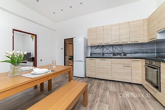 Moderní kuchyň s dřevěnou podlahou, vestavěné skříně a světlý design.