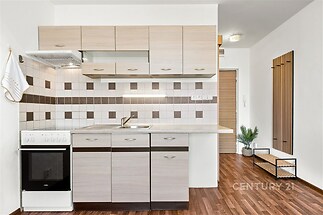Moderní kuchyň s parketovou podlahou, světlými dřevěnými skříňkami a dlaždičkovým obkladem, světlý a účelný design