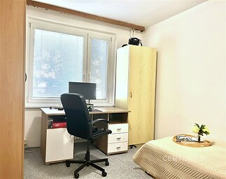 Pracovní kout s moderním stolem, roletami na oknech a kobercem, prostorná skříň, ideální pro home office nebo studium.