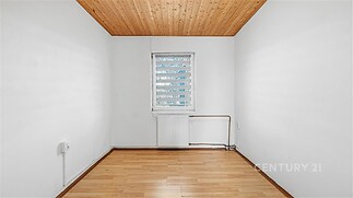 Menší pokoj s parketovou podlahou, dřevěným stropem a velkým oknem, které zajišťuje dostatek přirozeného světla, ideální pro renovaci.