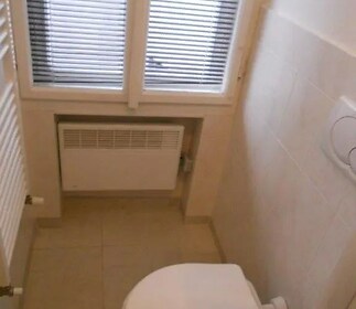vana s radiátor, kachličková podlaha, a přirozené světlo