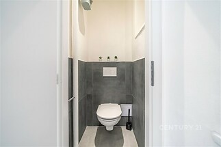 Moderní toaleta s dlažbou, světlé stěny a minimalistický design vytváří čistý a elegantní prostor, ideální pro moderní bydlení.