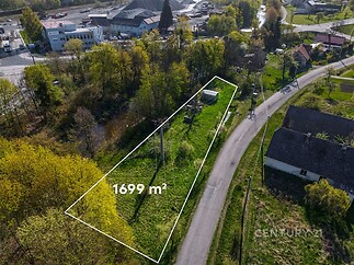 Pozemek o rozloze 1699 m² obklopený zelení a stromovými porosty s přístupem z klidné asfaltové cesty, ideální pro stavbu rodinného domu.