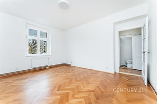 Světlý obývací pokoj s parketovou podlahou, velkými okny a moderním rekonstrukovaným designem nabízí prostorný interiér.