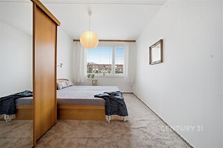 Prostorná ložnice s kobercem, vestavěnou skříní a velkými okny, které zajišťují dostatek světla a moderní vzhled.