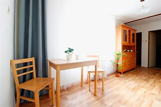 Světlá jídelna s parketovou podlahou, velká okna a dřevěný nábytek, moderní styl, světelné závěsy a vestavěné poličky enhancují prostor.