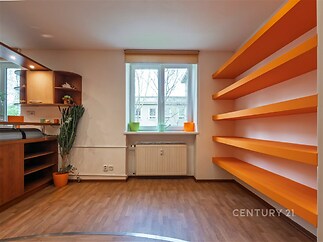 Světlý obývací pokoj s parketovou podlahou, velkým oknem a vestavěnými policemi v moderním stylu.